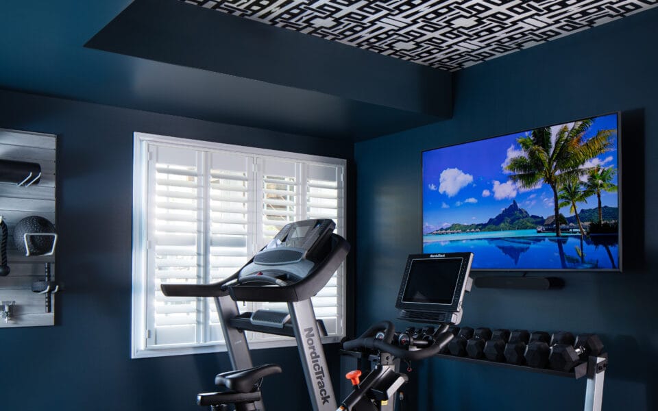 A workout room with exercise equipment, blue walls, and a television