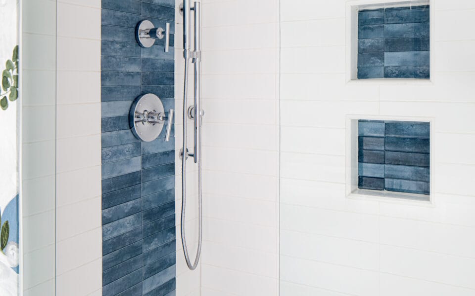 A clean, modern shower with white and blue tiles and stainless steel features