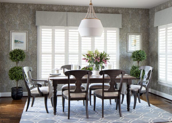 A light, airy dining room with a table, chairs, and window treatments