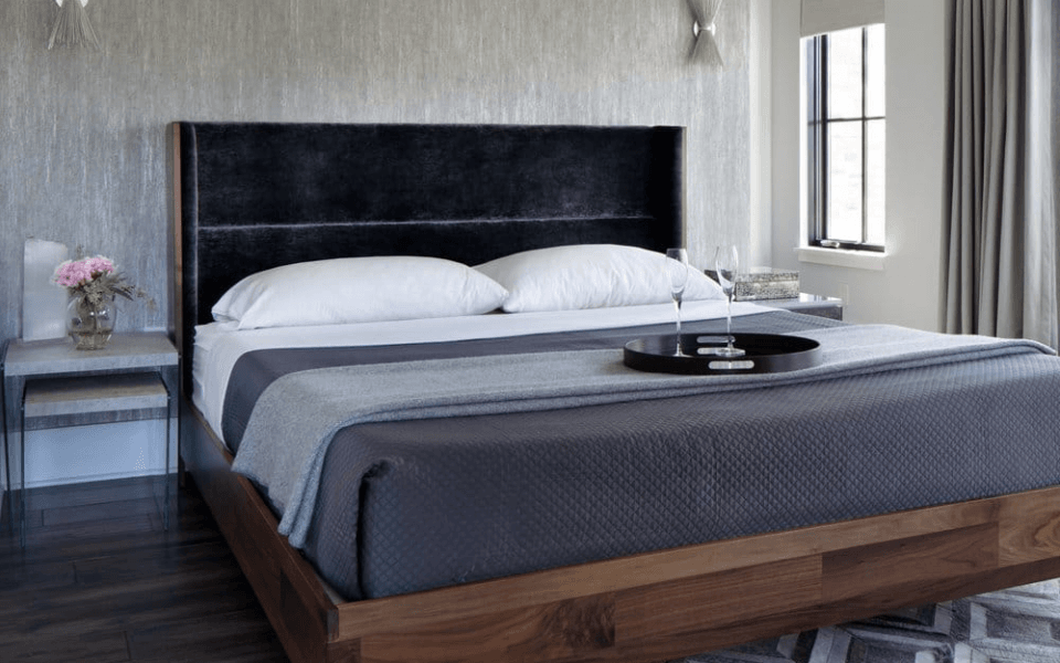 a bedroom with textured wallpaper and a modern platform bed with dark bedding
